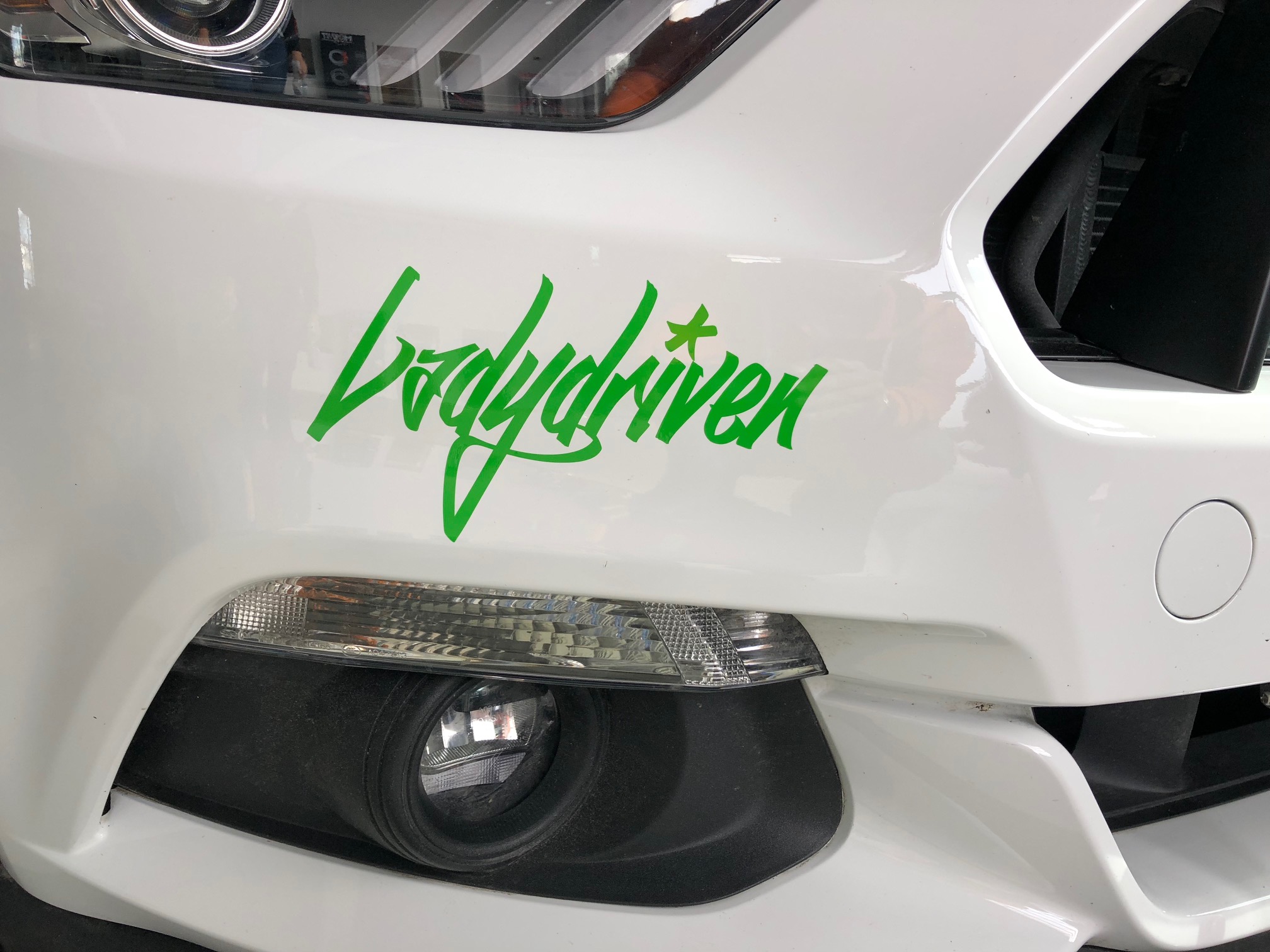 Grüner Ladydriven Aufkleber auf der Front eines weißen Autos