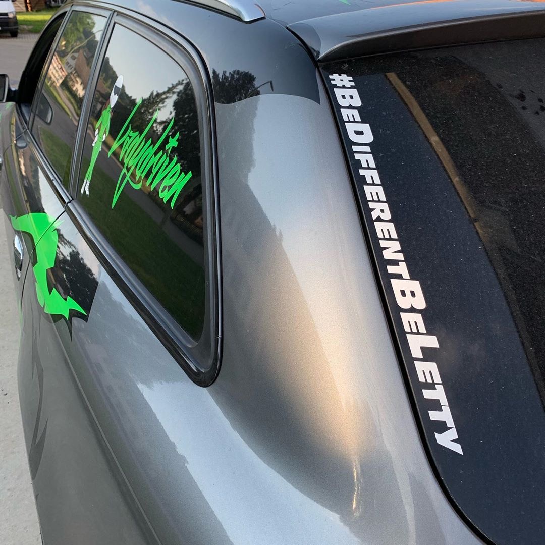 Weißer #BeDifferentBeLetty Aufkleber auf der Heckscheibe eines grauen Autos